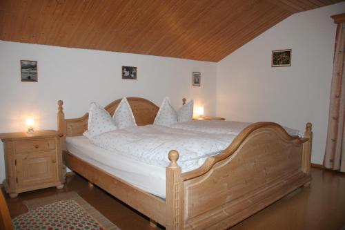 - une chambre dotée d'un lit en bois avec des draps et des oreillers blancs dans l'établissement Ferienwohnung Heilingbrunner, à Bad Wiessee