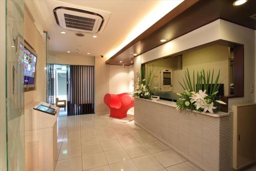 a lobby with a reception desk and a red chair at HOTEL DCUBE in Tokyo