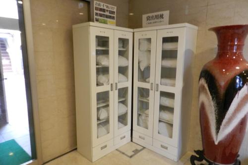 a white cabinet with glass doors next to a vase at Check In Matsuyama in Matsuyama