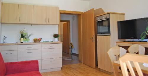 a kitchen with white cabinets and a flat screen tv at Gasthof Weidmannshof in Bressanone