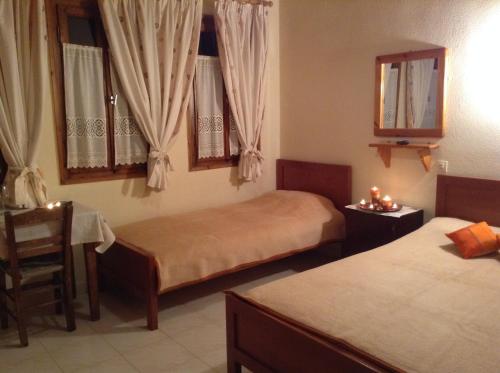 a bedroom with two beds and a table and a chair at Menelaos Apartments in Lefokastro