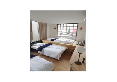 a room with three beds and a window at Nagoya Hostel The Three Smiles / Vacation STAY 13462 in Nagoya