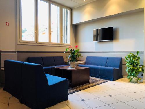 a waiting room with blue couches and a tv at Hotel Delfina in Signa
