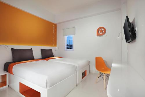 een slaapkamer met een wit bed en een oranje muur bij Starlet Hotel Serpong in Serpong