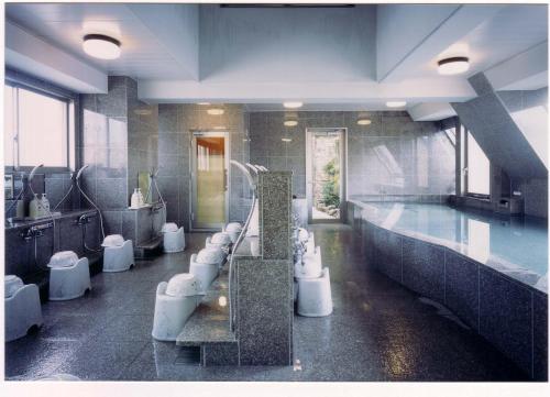 a bathroom with a bunch of toilets and a swimming pool at Hotel Sambancho in Matsuyama