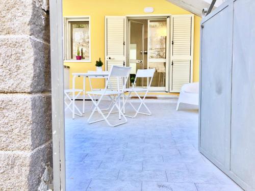 patio z krzesłami, stołem i żółtą ścianą w obiekcie Villa Lattea w mieście Aci Trezza