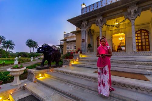 a woman in a pink dress standing in front of a building at Dev Shree Deogarh in Devgarh