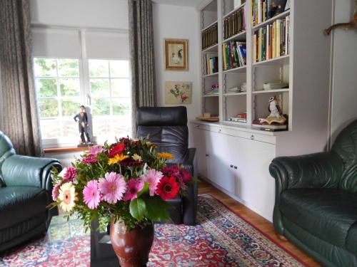 a living room with a table with a vase of flowers at B&B Domein Rodin in Oud-Turnhout