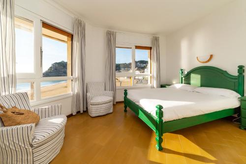 a bedroom with a green bed and a couch and windows at Edificio Tropicana in Tossa de Mar