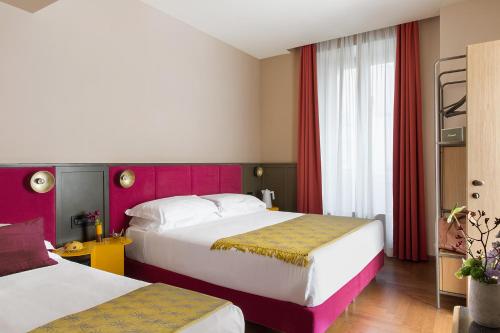 a hotel room with two beds and red curtains at Condominio Monti Boutique Hotel in Rome
