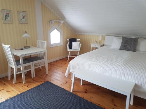 um quarto com uma cama branca, uma mesa e cadeiras em Hedesunda Bed & Breakfast em Hedesunda