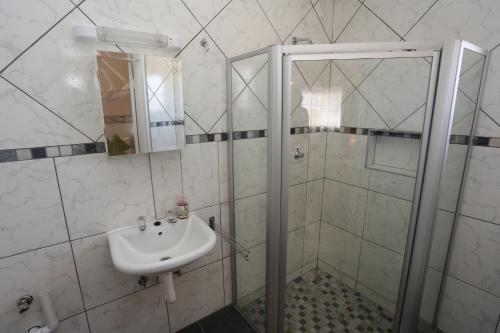 a bathroom with a shower and a sink at Orange House Self Catering in Aus