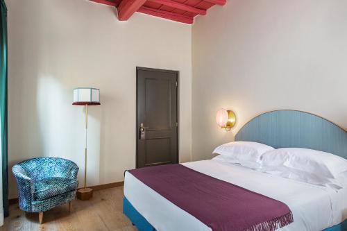 a bedroom with a bed and a chair and a lamp at Condominio Monti Boutique Hotel in Rome
