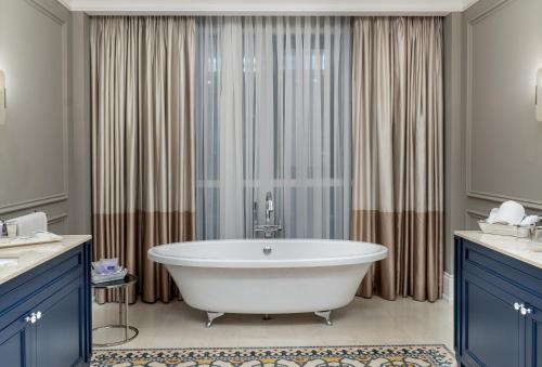 a bath tub in a bathroom with blue cabinets at Landmark Amman Hotel & Conference Center in Amman