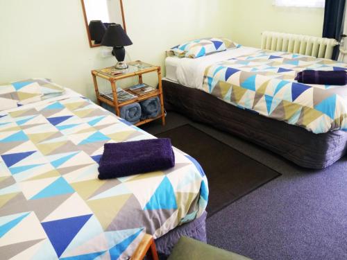 a bedroom with two beds and a table with a lamp at Braemar House B&B and YHA Hostel in Whanganui