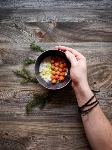 a person holding a bowl of food on a wooden table at Lapland Hotels Bulevardi in Helsinki