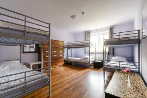 a room with three bunk beds and a table at Apartamenty Stara Praga - Wiatraczna in Warsaw