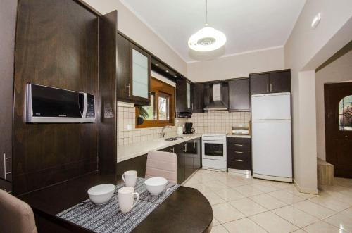 eine Küche mit einem schwarzen Tisch und einem weißen Kühlschrank in der Unterkunft Horio House in Límni