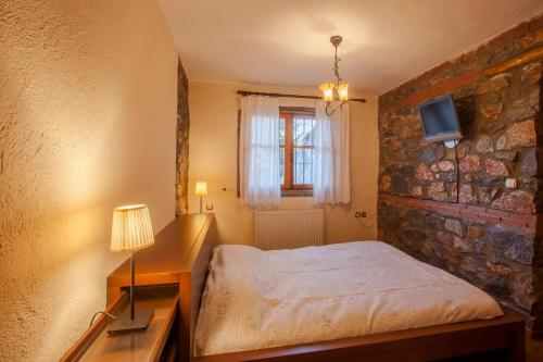a bedroom with a bed and a stone wall at Villa Palaios Agios Athanasios in Palaios Agios Athanasios