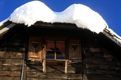 a window on a log cabin with snow on the roof at Planinarski dom "Tornik" Zlatibor in Ribnica