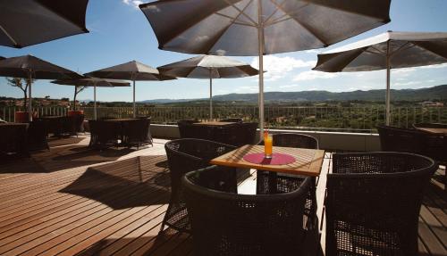 a wooden deck with a table and chairs with umbrellas at Hotel Casino Chaves in Chaves