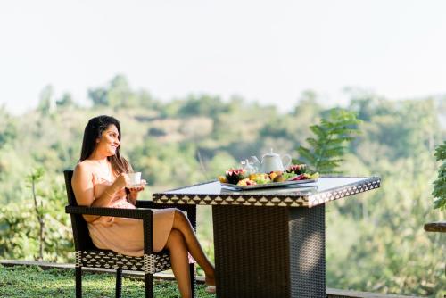 a woman sitting at a table with a drink at Cogent Holiday Home in Gelioya