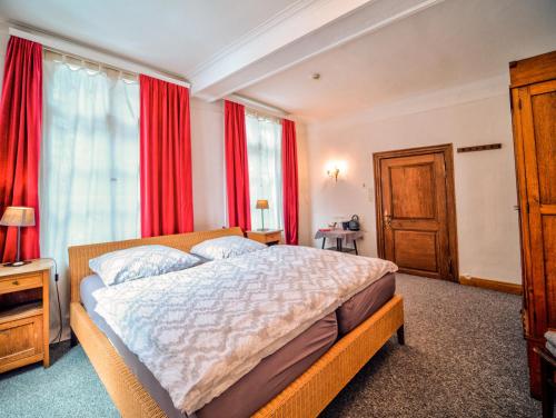 a bedroom with a large bed with red curtains at Haus Stehlings in Monschau