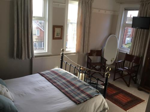 a bedroom with a bed and two chairs and windows at Lee-Side B&B in Robin Hood's Bay
