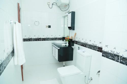 Baño blanco con aseo y lavamanos en Lourdes Hotel, en Nuwara Eliya