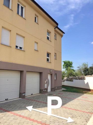 a house with two garage doors and a driveway at Bayview Apartment in Selce