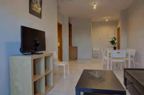 a living room with a flat screen tv and a table at Apartamentos Centro 1 El Puerto de Santa Maria in El Puerto de Santa María