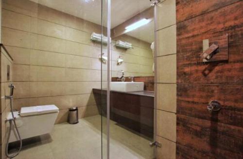 a bathroom with a toilet and a sink and a shower at Woodies Bleisure Hotel in Kozhikode