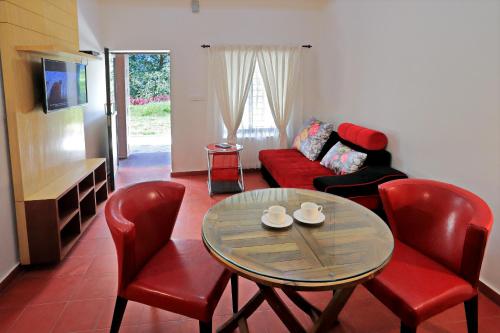 sala de estar con mesa, sillas y sofá en Ottway Hills Near Mattupetty Dam, en Munnar