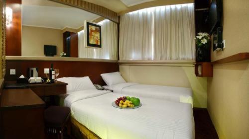 Habitación con 2 camas y un bol de fruta. en Oriental Lander Hotel en Hong Kong