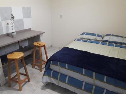a bedroom with a bed and two stools at Hostel Cult MR Alagoas in Arapiraca