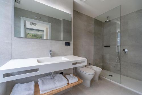a bathroom with a sink and a toilet and a mirror at Hotel Distrito Oeste in Donostia-San Sebastián