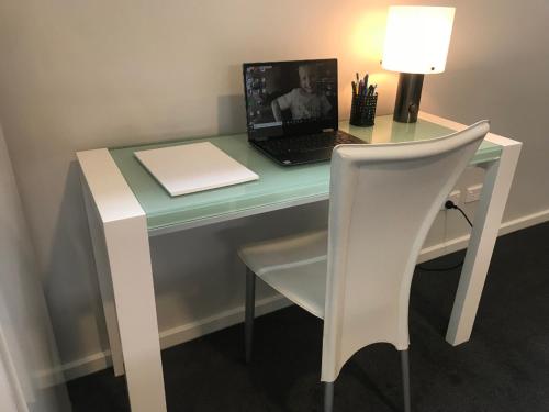 a desk with a laptop computer on it with a chair at Adelaide Hills Escape in Woodside