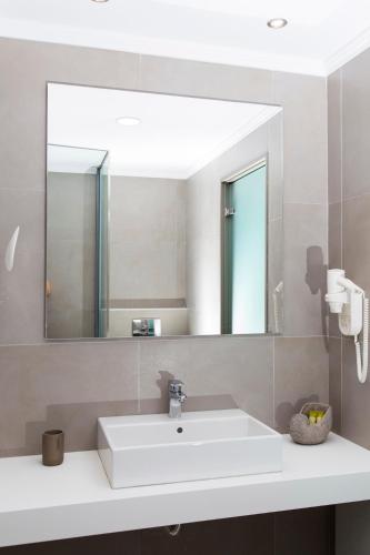 a bathroom with a white sink and a mirror at Lindos Del Mar Suites - Adults Only in Líndos