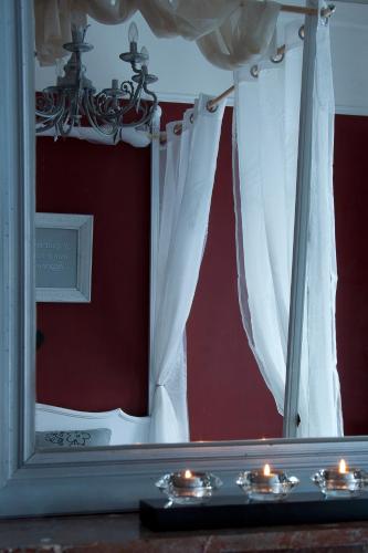 a mirror with white curtains and candles on a table at B&B Cambiare in Eeklo