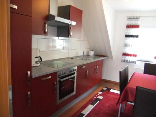 una pequeña cocina con armarios rojos y fregadero en Ferienwohnung Morgen, en Valwig