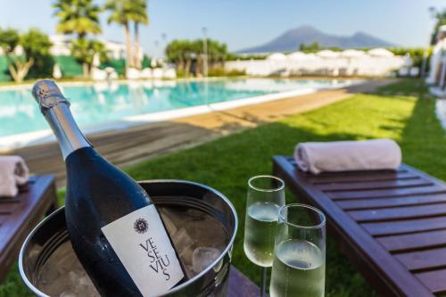 eine Flasche Wein in einem Eimer neben zwei Gläsern in der Unterkunft Resort & Winery Bosco De Medici in Pompei