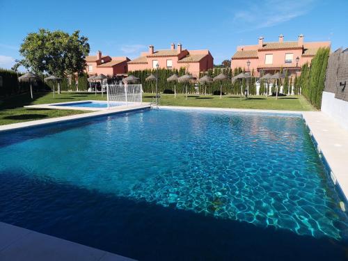 a swimming pool with blue water in front of a house at Villa Aznalcazar in Sanlúcar la Mayor