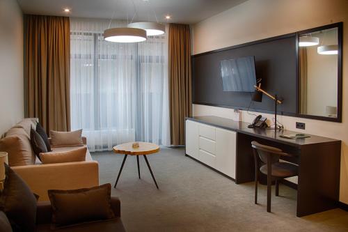 uma sala de estar com um sofá e uma secretária com uma televisão em Sobi Hotel em Vyshhorod