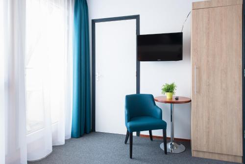 a room with a blue chair and a table and a television at Hotel Nes in Nes