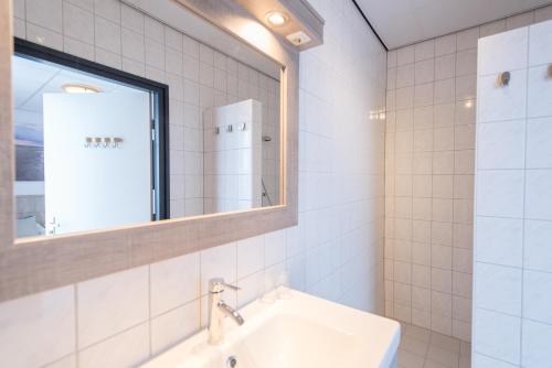 a white bathroom with a sink and a mirror at Hotel Nes in Nes