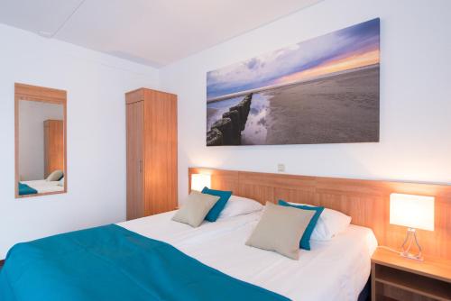 a bedroom with a bed and a painting on the wall at Hotel Nes in Nes
