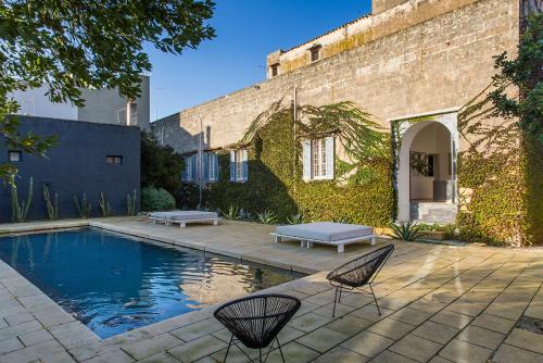 a backyard with a pool and two chairs and a building at Palazzo Daniele in Gagliano del Capo