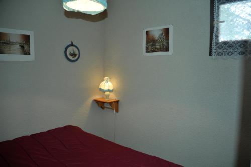 a bedroom with a bed and a lamp on a table at location 4 pers Angélique t 2 résidence les bords du lac lac in Le Lauzet-Ubaye