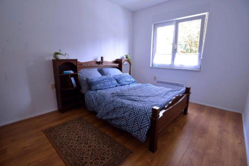 sypialnia z łóżkiem z niebieską kołdrą i oknem w obiekcie Ferienpark Ebertswiese w mieście Seligenthal