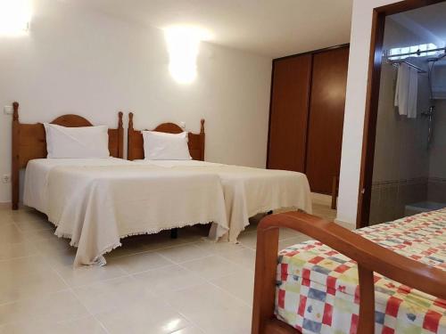 アルマカオ・デ・ペラにあるCasa da Praiaのベッドルーム1室(白いシーツが備わるベッド2台付)